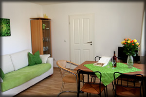 Ferienwohnung für bis zu 3 Personen, Wohnzimmer mit integrierter Küchenzeile. links: Die Couch lässt sich in ein Schlafsofa verwandeln.